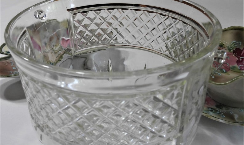 May include: A clear glass cup with a diamond pattern. The cup has a gold rim and is made of thick glass.