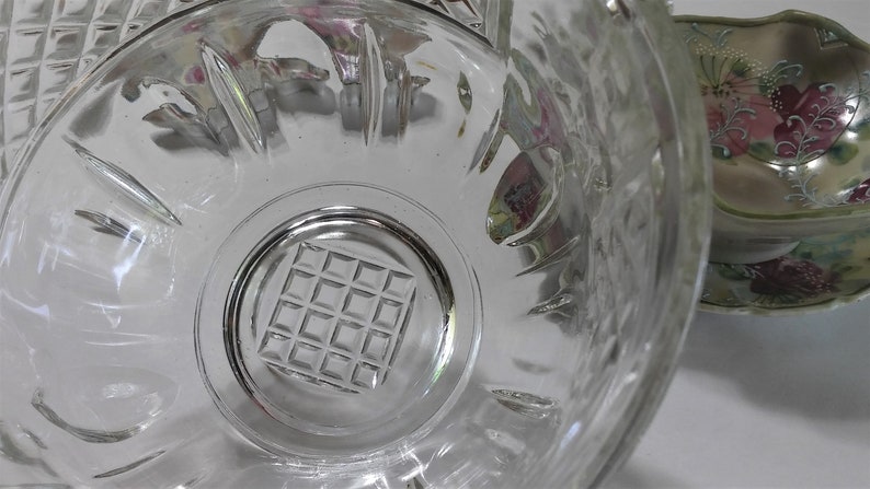 May include: A clear glass bowl with a grid pattern on the bottom. The bowl has a scalloped edge and is made of thick glass.