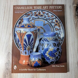 May include: A book titled "Chameleon Ware Art Pottery: A Collector's Guide to George Clews" by Hilary Calvert. The cover features a blue and white ceramic vase with intricate floral designs. The book is a Schiffer Book for Collectors and includes a price guide.