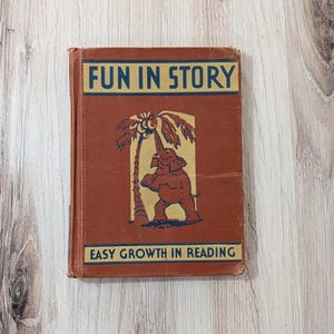 Może przedstawiać: Vintage książka dla dzieci zatytułowana "FUN IN STORY" z ilustracją słonia sięgającego po palmę. Okładka jest czerwonobrązowa z niebieskim i złotym tekstem. Podtytuł brzmi "EASY GROWTH IN READING".