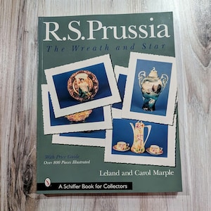 Puede incluir: Un libro verde titulado "R.S. Prussia The Wreath and Star" con una guía de precios y más de 800 piezas ilustradas. La portada del libro presenta fotos de varias piezas de porcelana, incluyendo un plato, una tetera y un jarrón.