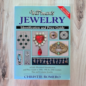 May include: A book titled "Warman's Jewelry" with the subtitle "Identification and Price Guide." The cover is light blue and features jewelry illustrations. The book is a 3rd edition and is by Christie Romero.