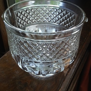 May include: A clear glass bowl with a diamond pattern. The bowl is sitting on a wooden surface.