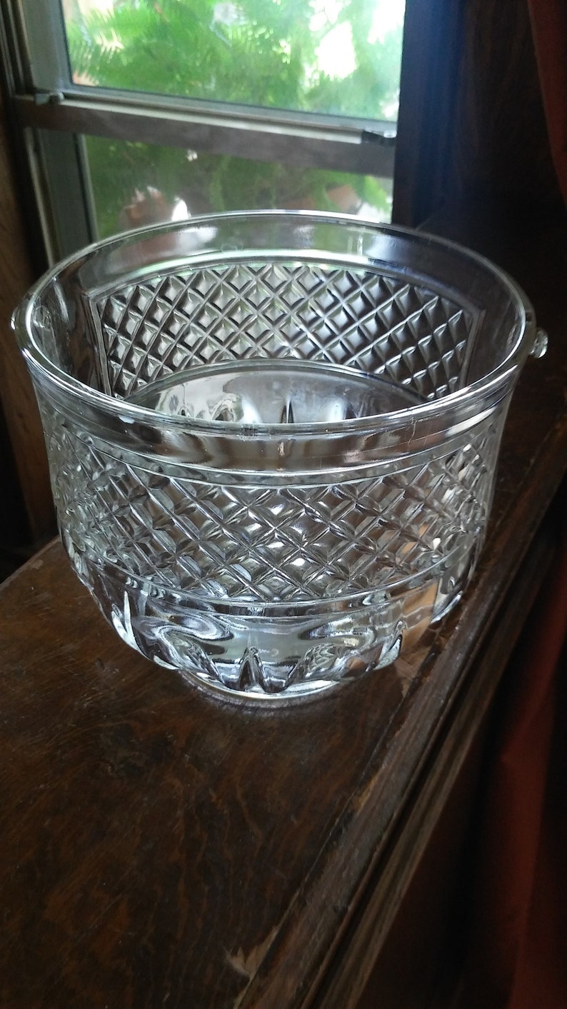 May include: A clear glass bowl with a diamond pattern. The bowl is sitting on a wooden surface.