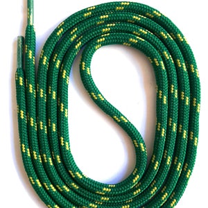 Può includere: Lacci per scarpe con motivo verde e giallo. I lacci sono di un verde vibrante con un motivo ripetuto di piccoli trattini gialli. Gli aghetti sono verdi. I lacci sono arrotolati su uno sfondo bianco.