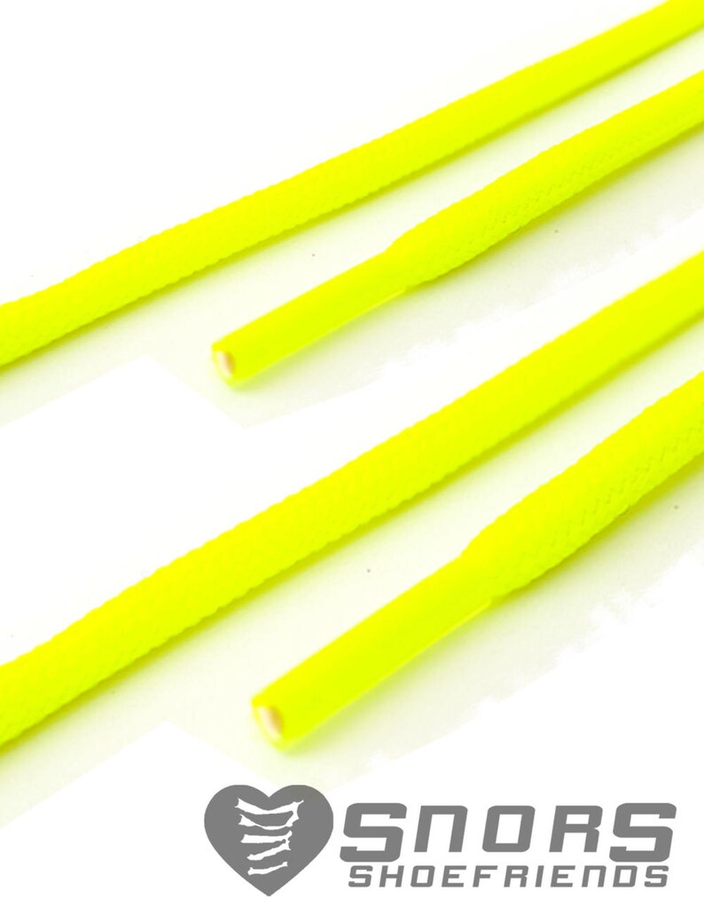 Op de afbeelding: Close-up van verschillende neongele schoenveters tegen een witte achtergrond. De veters zijn cilindrisch met een getextureerd oppervlak. Het logo "SNORS SHOEFRIENDS" is rechtsonder zichtbaar.