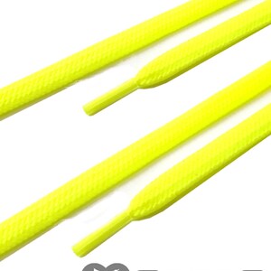 May include: Bright yellow shoelaces with textured surfaces are displayed against a white background. The shoelaces are angled, showcasing their shape and design. The logo "SNORS SHOEFRIENDS" is visible at the bottom.