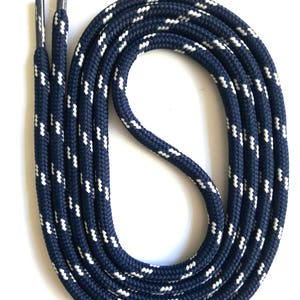 Peut inclure: Lacets de chaussures bleus marine et blancs à motifs. Les lacets sont faits d'une matière épaisse et durable semblable à une corde. Le motif blanc est une série de petits tirets espacés. Les embouts sont argentés.