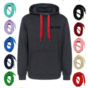 May include: A dark gray hoodie with red drawstrings, and the text "Snoas ShoeFriends" in black. Surrounding the hoodie are various colored shoelaces, including green, orange, purple, blue, white, black, and pink.