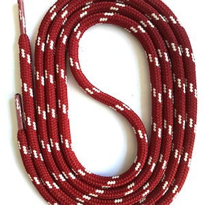 Könnte beinhalten: Rot-weiß gemusterte Schnürsenkel. Die Schnürsenkel sind tiefrot mit einem sich wiederholenden Muster aus kleinen weißen Strichen. Die Aglets sind dunkelrot. Die Schnürsenkel sind in einem kreisförmigen Muster angeordnet.