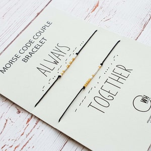 Puede incluir: Pulseras de pareja con código Morse sobre una tarjeta blanca. Una pulsera deletrea "ALWAYS" y la otra "TOGETHER" en cuentas doradas y blancas. La tarjeta tiene el texto "MORSE CODE COUPLE BRACELET".