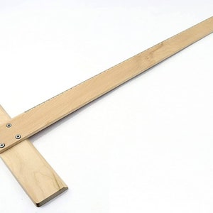 Pode incluir: Um esquadro de madeira com um braço longo e retangular e um braço mais curto e perpendicular. A marca "liquidraw" está impressa em vermelho no braço mais curto. O esquadro é feito de madeira clara e tem um furo na extremidade do braço longo.