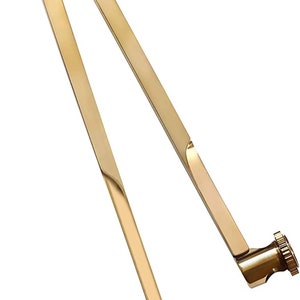 Può includere: Un compasso dorato con una punta affilata e una manopola nella parte superiore. Il compasso è in metallo e ha un design elegante e professionale.