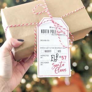 May include: A wrapped gift box with a red and white string tied around it. A tag reads "North Pole Express" with "Naughty" and "Nice" check boxes, and "Santa Claus" at the bottom. The box is held by a hand.