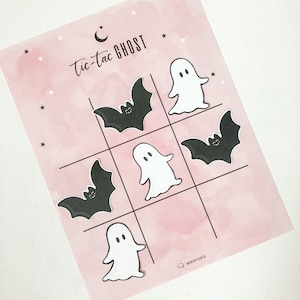 May include: A pink and white tic-tac-toe game board with the words "tic-tac GHOST" printed at the top. The game board has nine squares with images of ghosts and bats in each square.