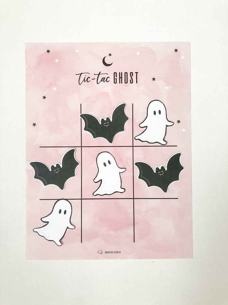 May include: A pink and white printable tic-tac-toe game with a crescent moon and stars. The game features ghosts and bats.