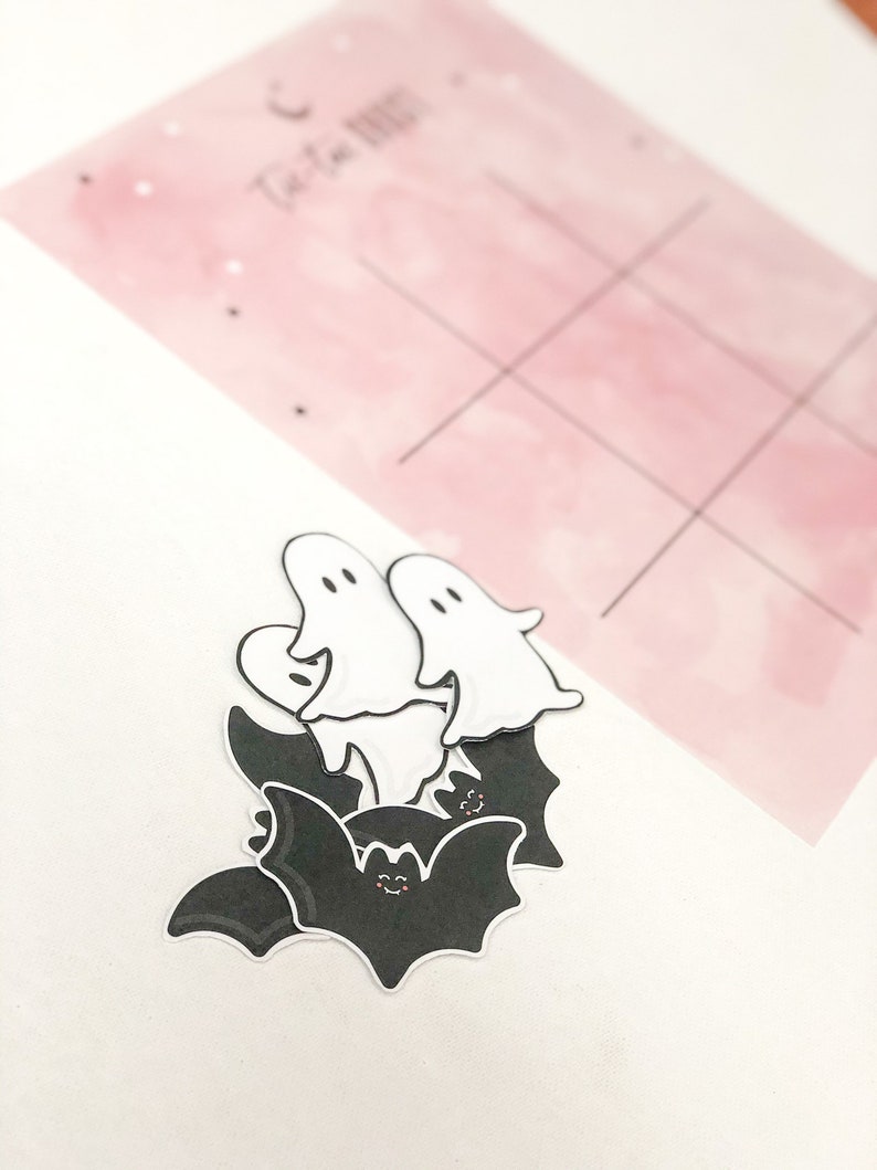 May include: A set of Halloween-themed stickers featuring black bats with white eyes and white ghosts with black eyes. The stickers are on a white background.