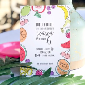 Puede incluir: Una tarjeta de invitaci&oacute;n colorida con un tema de frutas. La tarjeta dice "Tutti Frutti" y "Ven a celebrar a nuestro adorable Jensen que cumple 6 a&ntilde;os". La invitaci&oacute;n es para una fiesta el s&aacute;bado 18 de agosto de 1:00 a 3:00 en 1940 Cascade Falls Ln. Tambi&eacute;n dice "&iexcl;Trae tu traje de ba&ntilde;o para nadar!"