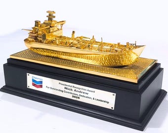 May include: A gold-colored ship model trophy on a black base. The trophy includes a plaque with text that reads "Presidential Recognition Award" and the Chevron logo. The ship model is highly detailed.
