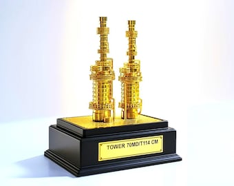May include: Two gold-colored tower sculptures on a black base with a gold plaque. The plaque reads "TOWER 70MD/T114 CM". The towers are highly detailed and stand on a gold-colored platform.