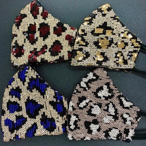 May include: Four sequined face masks with different animal print designs. The masks are black with gold, red, blue, and white sequins.