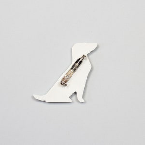 Pu&ograve; includere: Broche a forma di cane in ceramica bianca con una spilla d'argento sul retro.