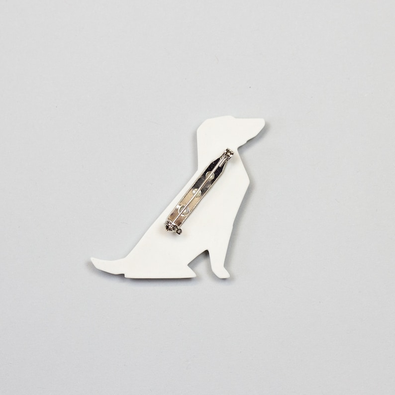 Pu&ograve; includere: Broche a forma di cane in ceramica bianca con una spilla d'argento sul retro.