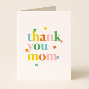 K&ouml;nnte beinhalten: Eine gefaltete Gru&szlig;karte mit den Worten &bdquo;thank you mom&ldquo; in farbenfrohen Buchstaben im Retro-Stil. Der Text wird durch kleine Blumen- und Herzillustrationen in verschiedenen Farben auf cremefarbenem Hintergrund akzentuiert.