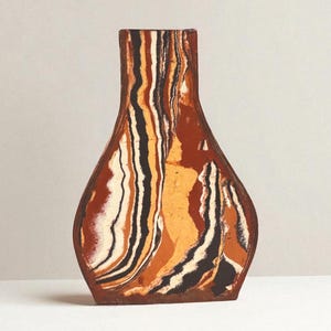 May include: A decorative vase with a unique, layered design. The vase features vertical stripes in shades of brown, orange, black, and white. The vase has a wide base and a narrow neck, creating an elegant silhouette.