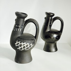 May include: Two black ceramic vases with white geometric designs. The vases are shaped like stylized roosters with a spout and a handle.