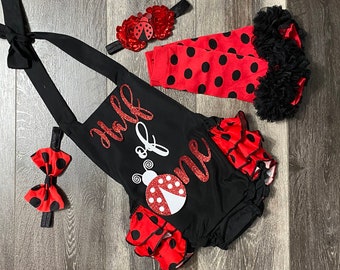 Può includere: Un completo per neonato a tema coccinella nero e rosso con un body nero, leggings a pois rossi e neri, una fascia per capelli rossa e nera con una coccinella e un papillon rosso e nero. Il body ha la scritta "Half of One".