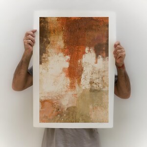 May include: A framed abstract painting with a textured surface. The painting features shades of brown, orange, and white.