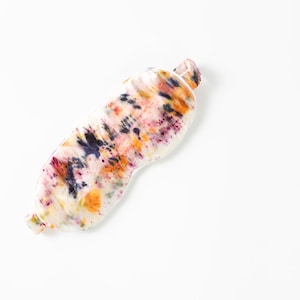 May include: A colorful sleep mask with a tie-dye pattern in shades of orange, yellow, purple, and blue.