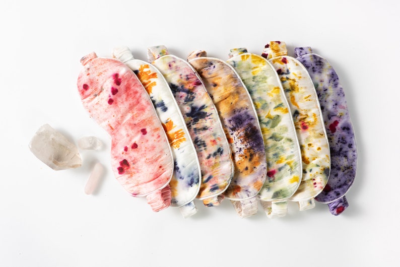 May include: A set of six colorful sleep masks with tie-dye patterns. The masks are made of soft fabric and have a white trim.