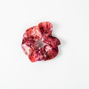 Puede incluir: Un coletero de pelo de color rojo y blanco con estampado tie-dye.
