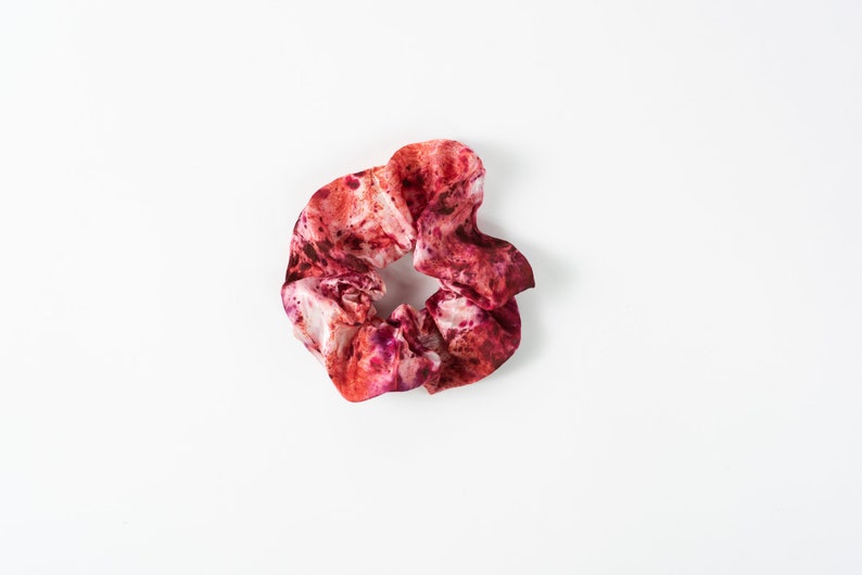 Puede incluir: Un coletero de pelo de color rojo y blanco con estampado tie-dye.