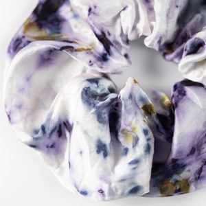 Puede incluir: Un scrunchie blanco con un estampado floral morado y azul.