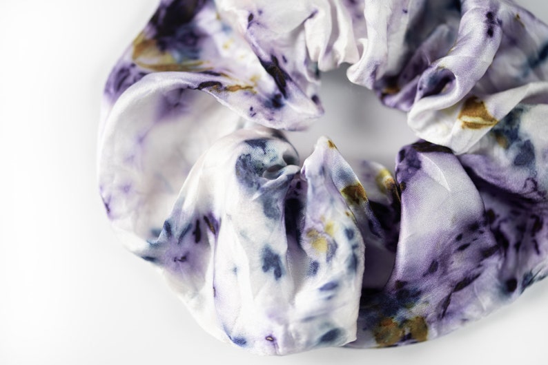 Puede incluir: Un scrunchie blanco con un estampado floral morado y azul.