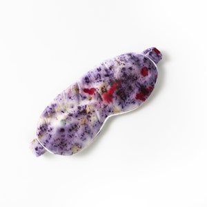 May include: A purple and white sleep mask with a floral pattern. The mask is made of silk and has a white trim.
