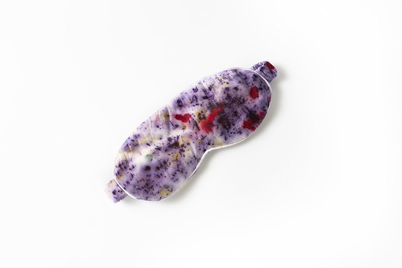 May include: A purple and white sleep mask with a floral pattern. The mask is made of silk and has a white trim.