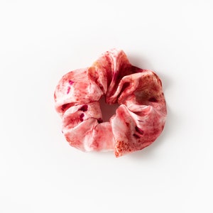 Puede incluir: Un scrunchie de tela con estampado rosa y rojo.