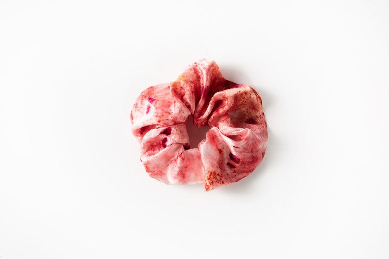 Puede incluir: Un scrunchie de tela con estampado rosa y rojo.