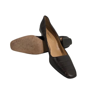 May include: A pair of brown leather pumps with a square toe and a low heel. The shoes have a textured, crocodile-like pattern. The brand name "Ralph Lauren" is visible inside one shoe.