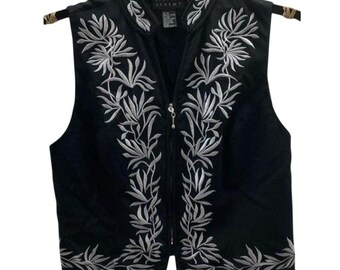 May include: Black vest with silver floral embroidery. The vest has a V-neck, a zipper closure, and a decorative silver zipper pull. The vest is hanging on a black hanger.