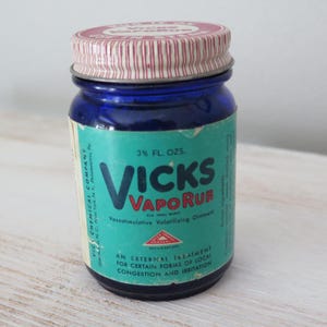 May include: A vintage Vicks VapoRub jar. The cobalt blue glass jar has a teal label with white text that reads "Vicks VapoRub." The lid is red and white striped. The jar contains 3 fl. oz. of ointment and is an external treatment for congestion and irritation.