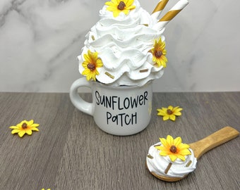 May include: White ceramic mug with the text "Sunflower Patch" and a white whipped cream topping with yellow sunflower decorations and two gold striped straws.
