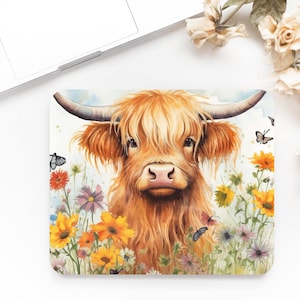 May include: A watercolor painting of a Highland cow with long, shaggy brown fur standing in a field of colorful wildflowers. Butterflies are flying around the cow and flowers.