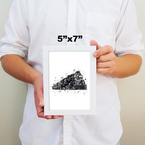May include: A framed black and white watercolor print of a vintage steam locomotive with gold accents. The print is 5 inches by 7 inches and is framed in a white frame.
