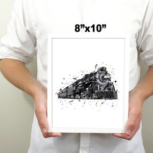 May include: A black and white watercolor print of a vintage steam locomotive train with a white background and black splatters. The print is framed and measures 8 inches by 10 inches.