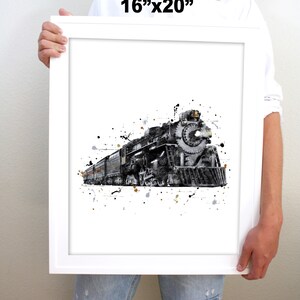 May include: A black and white watercolor print of a vintage steam locomotive with a splash of gold paint. The print is framed in a white frame and measures 16 inches by 20 inches.